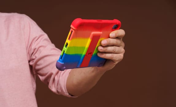 Sign of gay culture and LGBTQ pride representing man's hand holding pocket PC adorned in rainbow colors, Rainbow symbolism reflects diversity and inclusivity of LGBTQ community.