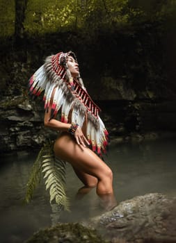 Naked girl in Native American headdresses poses sexually against the backdrop of wildlife