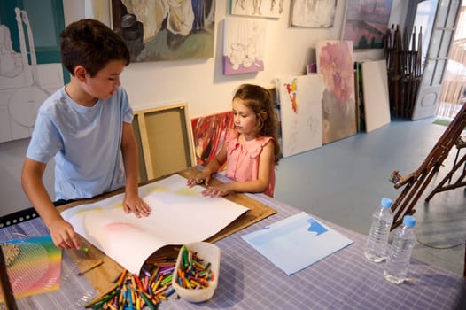 Adorable kids, a teenage boy and preschool girl drawing on white paper sheet during art class. People. Kids and hobbies