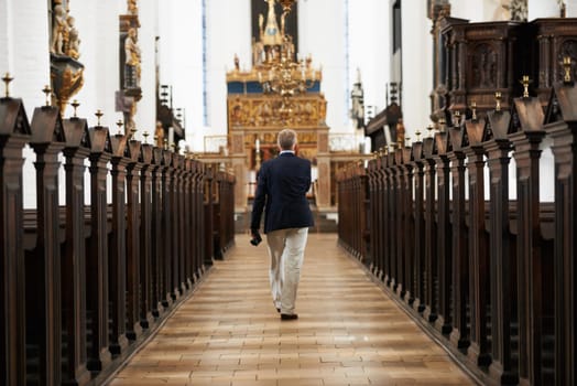 Walking, aisle and senior man in a church for sightseeing on a weekend trip, vacation or holiday. Faith, religion and back of holy elderly male person in retirement in worship cathedral in the city.