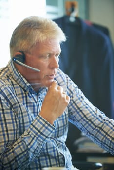 Senior businessman, face and thinking at call center for decision, choice or customer service at office. Mature man, consultant or agent in wonder with headphones for online advice or help workplace