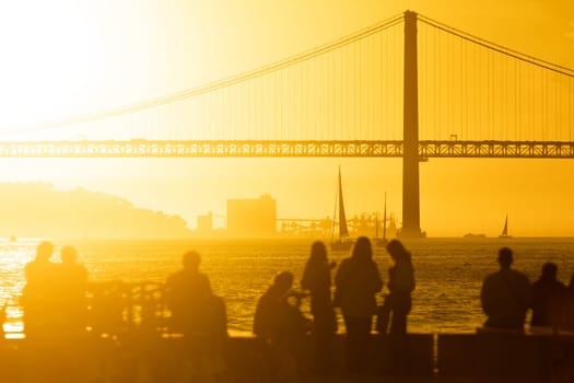 A Serene Sunset Overlooking a Majestic Bridge with a Group of People