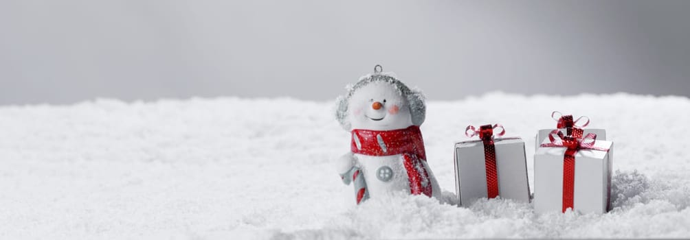 Merry christmas and happy new year greeting card . Happy snowman standing with christmas gifts on gray background