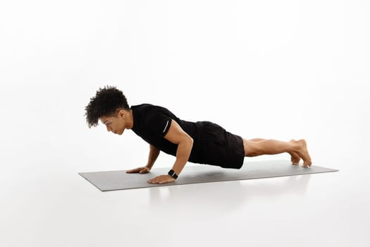 Brazilian young sportsman holding plank position over white studio background