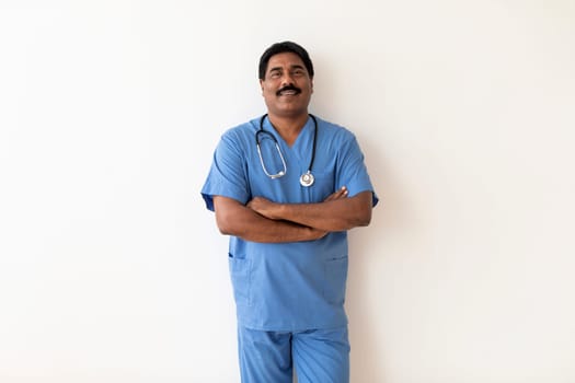 Medical Worker. Smiling Indian Male Doctor In Uniform Standing With Folded Arms
