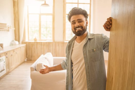 Bearded indian man smiling and welcoming guests in well-lit kitchen