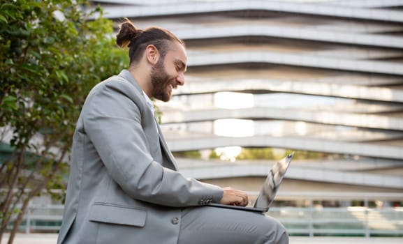 Outdoor Office. Happy Young Businessman Working With Laptop Outside Against Urban Building