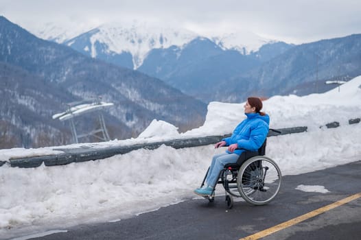 Caucasian woman in a wheelchair travels in the mountains in winter.