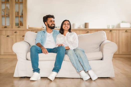 Content young indian couple sitting together on a sofa