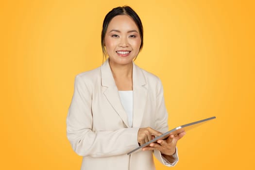 Positive confident young japanese businesswoman in suit, with tablet