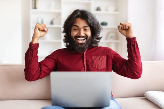 Emotional indian man using computer at home