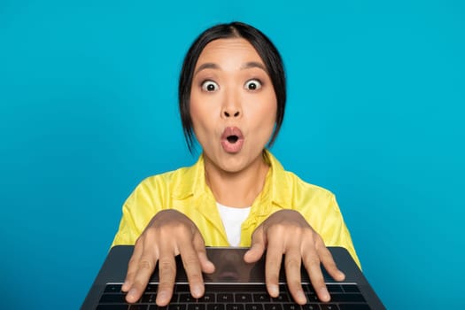 Shocked funny young chinese woman in casual chatting at keyboard computer