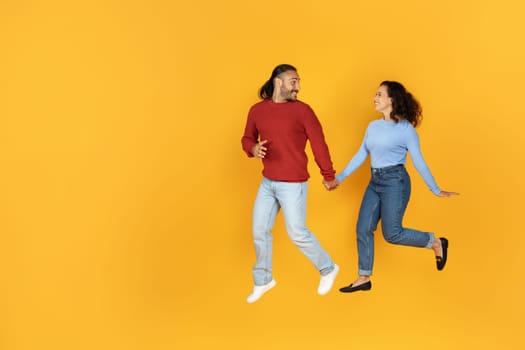 Joyful millennial couple holding hands and running