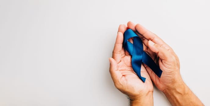 Supporting men's health awareness in November, this image features hands holding a blue ribbon
