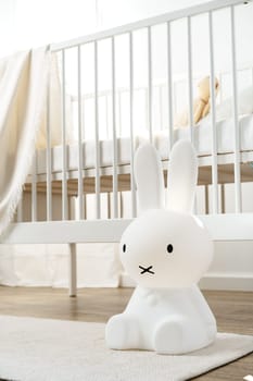 Baby wooden crib and toy rabbit in nursery room