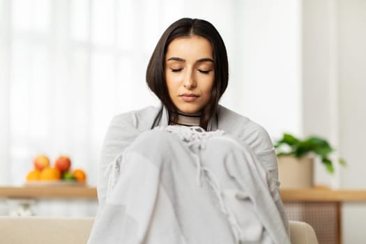 Unhappy millennial arab woman with closed eyes in plaid sick, suffer from cold, flu