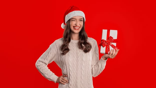 Woman Holds Wrapped Present With Bow Standing Over Red Background