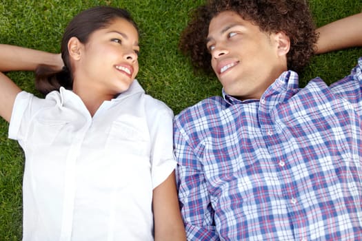 Love, happy and couple relax on grass outdoors for bonding, loving relationship and weekend. Dating, nature and above of man and woman together in garden for romantic picnic, holiday and vacation.