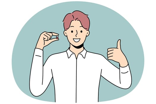 Smiling man hold pill show thumb up