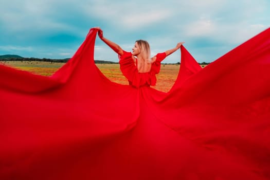 Woman Red Flying Dress. A blonde in a red dress against the sky. Rear view of a beautiful blonde woman in a red dress fluttering in the wind against a blue sky and clouds.