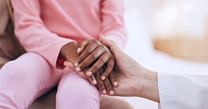 Closeup, holding hands and doctor with girl, healthcare and wellness with comfort, diagnosis and support. People, medical and professional with a patient, compassion and empathy with paediatrician