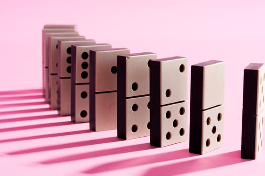 Row of domino tiles on pink studio background