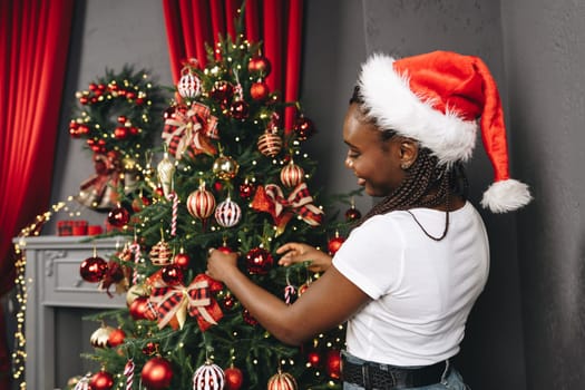 African woman preparing for winter holidays decorating Christmas tree