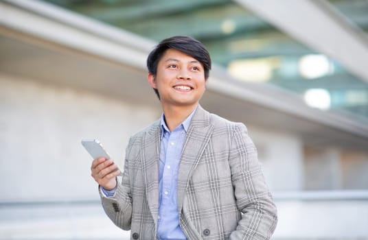 Asian entrepreneur man navigates smartphone in urban city area