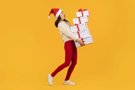 Lady carrying stack of Xmas presents boxes on yellow background