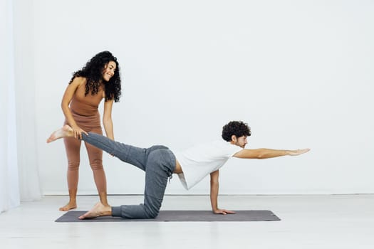 a woman helps a man do gymnastics warm-up exercises yoga