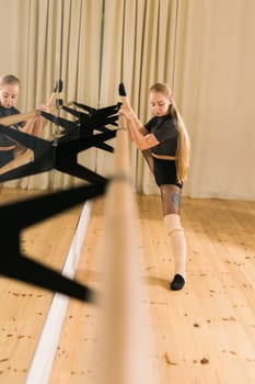Female ballet dancer practicing at barre in dance studio - dance and ballerina concept