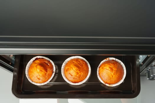 Electric mini oven and baked hot muffins close up
