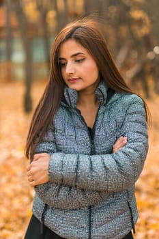 Beautiful indian woman generation z relaxing and feeling nature at autumn park in fall season copy space. Diversity and gen z youth