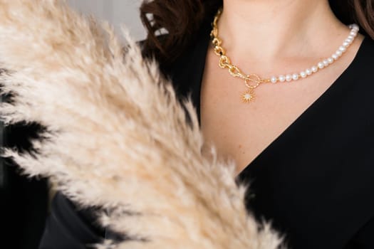 Close-up female in modern pearl and gold necklace chain with pendant. Handmade jewellery and accessories.
