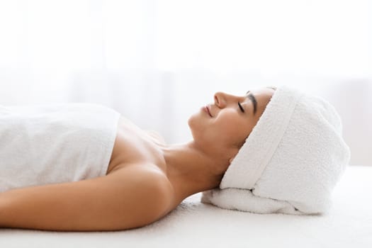Lady with closed eyes laying on massage table at spa