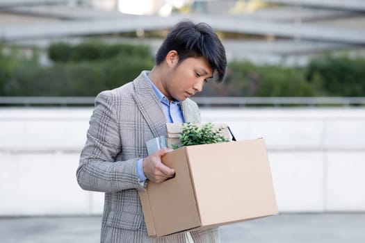 Korean businessman stands out of office building holds personal belongings