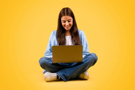 Glad caucasian teenager student lady use computer, typing and sit on floor