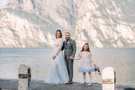 Italy, Lake Garda. Beautiful family on the shores of lake Garda in Italy at the foot of the Alps. Father, mother and daughter in Italy