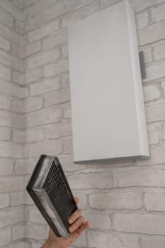A man changes the filter at the supply ventilation. Gadget for ventilation, disinfection and air purification of the apartment.