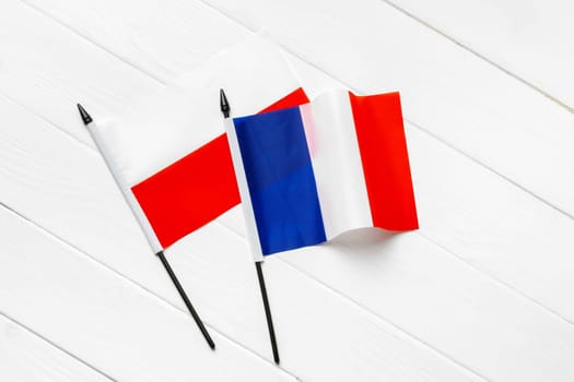 Flags of Poland and France on white wooden background