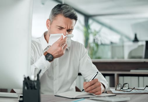 Business man blowing nose at desk in office for allergies, cold and sick virus while writing in notebook. Mature entrepreneur with tissue for infection, influenza or allergy risk while planning notes