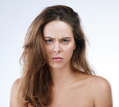 Portrait, messy hair and frown with an frustrated woman in studio on a white background for beauty. Damage, split ends or frizz and a young person looking unhappy with her haircare treatment
