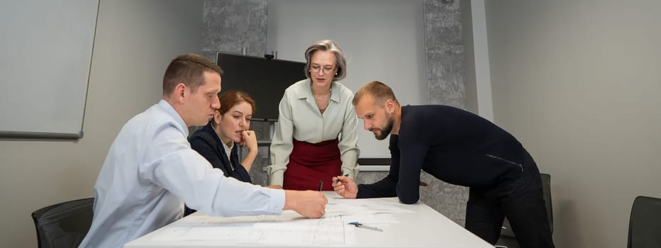 The female boss evaluates the work of subordinates. Designers engineers at a meeting.