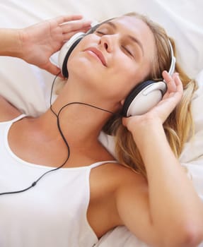 Happy woman, eyes closed and headphones for music on bed for relaxing. Closeup, female person and peaceful expression on face for listening, audio and streaming service for podcast, radio or song
