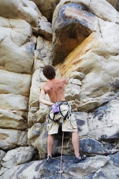 Man, rock climbing and rope on mountain or chalk bag for cliff grip, adventure holiday as athlete. Male person, exercise and challenge gear as cardio fearless, active discipline for extreme sports