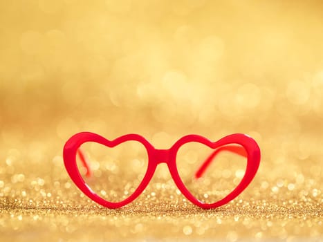 red hearts glasses on gold bokeh background