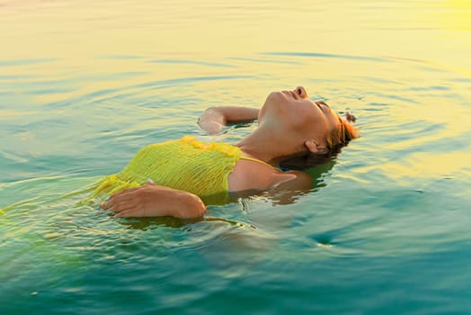 young woman immersed in water, illuminated by the rising sun.