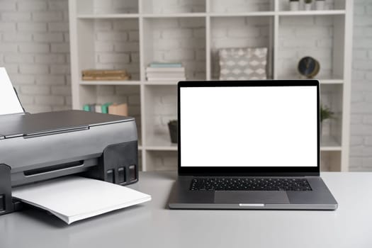 Printer and laptop on grey table in office