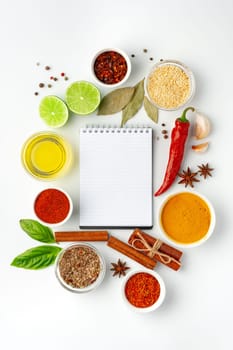 Blank notepad surrounded by different ingredients and spices on white background