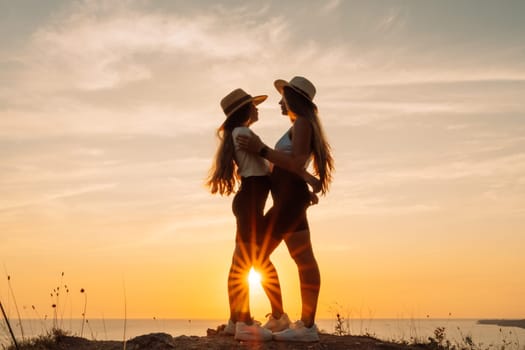 Mother daughter sunset. Mother and daughter stand on the beach, hugging and looking at each other enjoying the sunset.